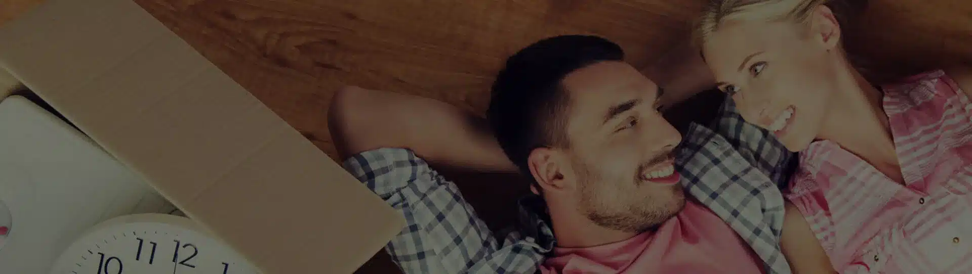 Zwei Personen liegen zwischen umzugskosten auf dem Boden der neuen Wohung und freuen sich