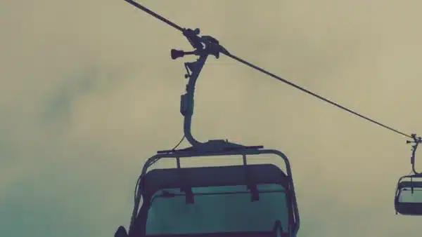 Sessellift fährt Ski und Snowboard Fahrer:innen nach oben auf den Berg