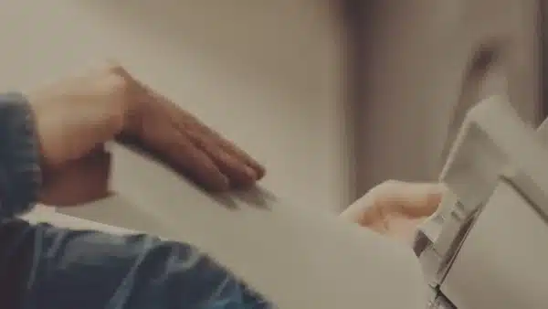 Jemand schiebt Papier in einen Drucker